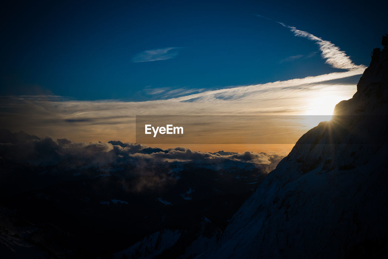 Scenic view of sunset at mountain over clouds against sky