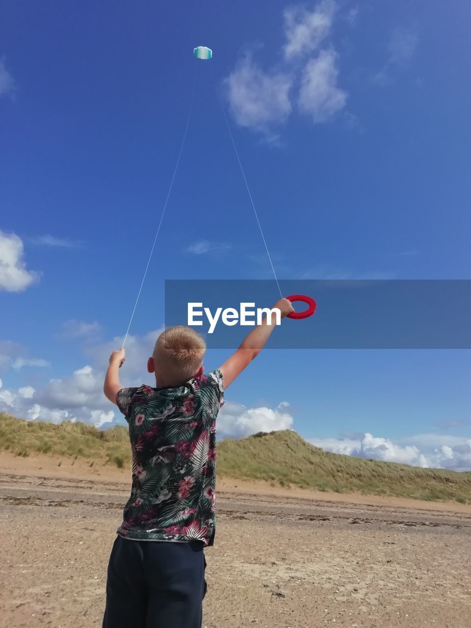 Rear view of boy flying kites against sky