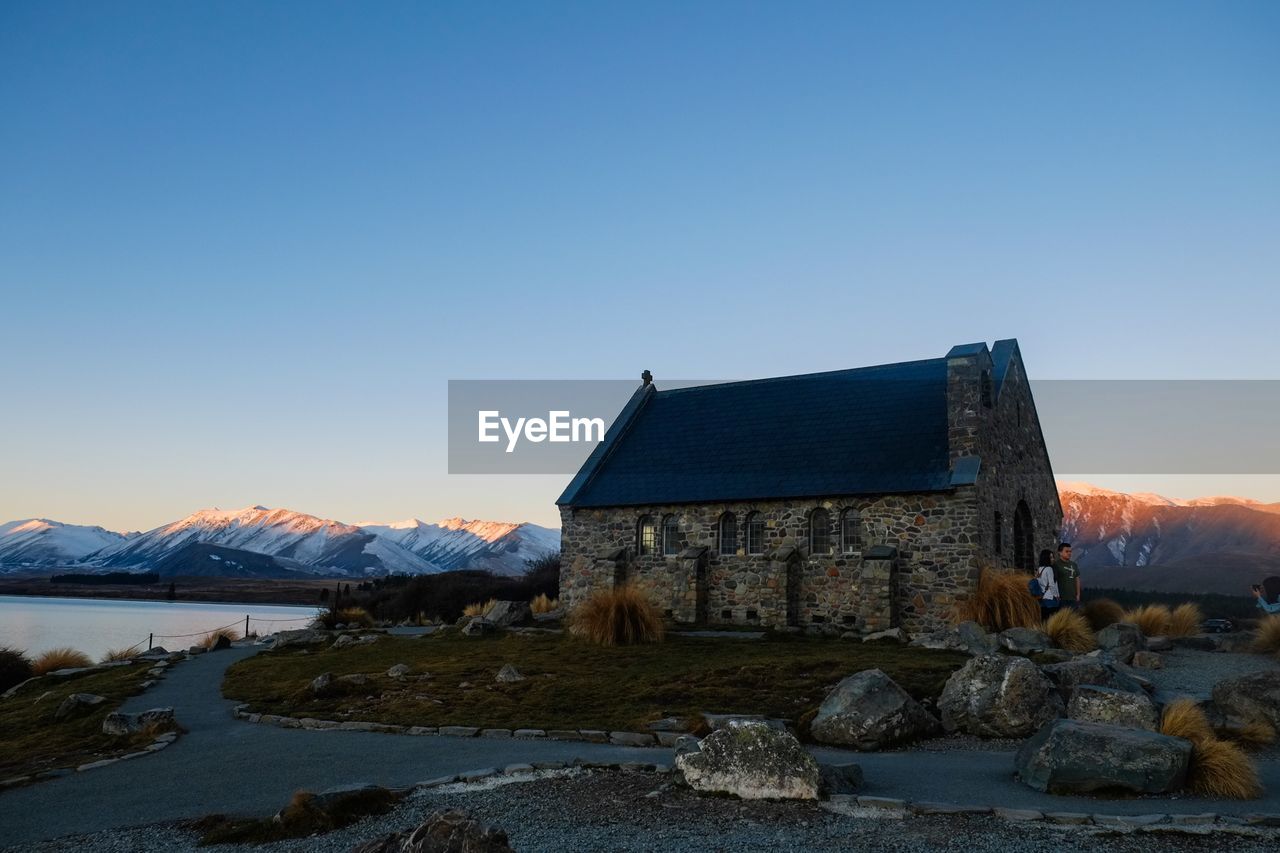 BUILDING BY LAKE AGAINST CLEAR BLUE SKY