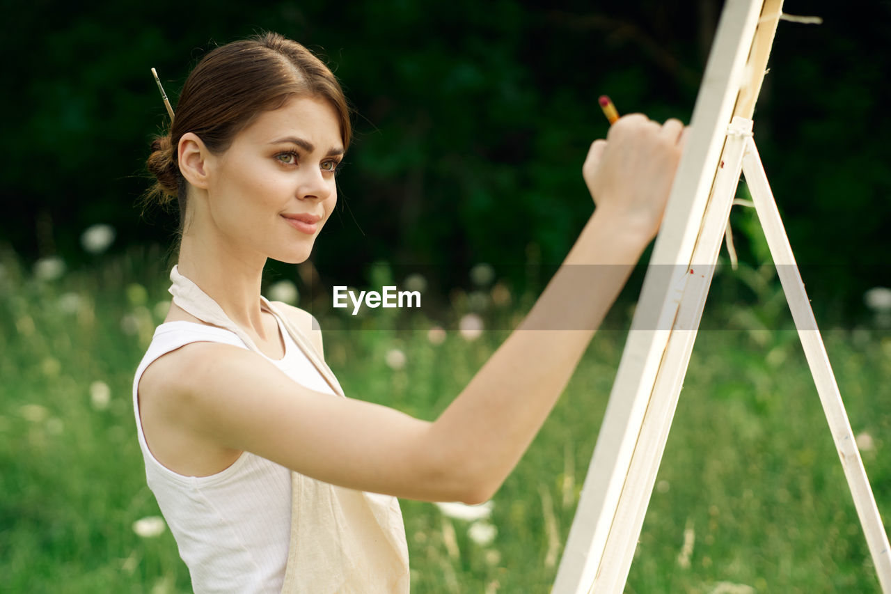 PORTRAIT OF YOUNG WOMAN HOLDING CAMERA