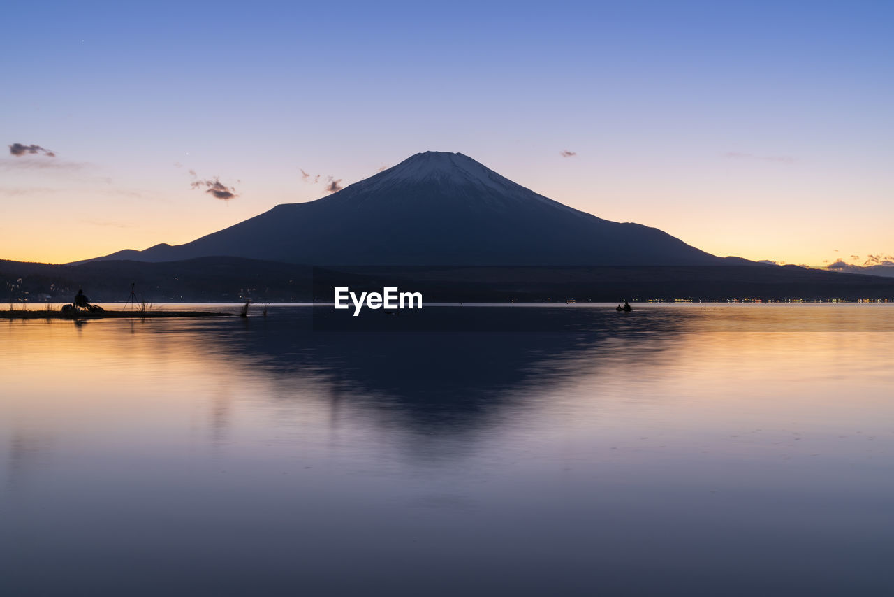 Scenic view of lake and mountain against sky during sunset