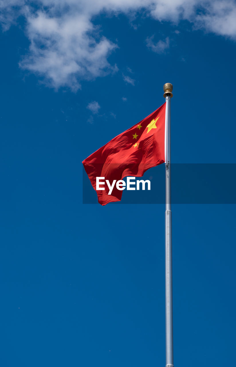 Low angle view of chinese flag waving against blue sky