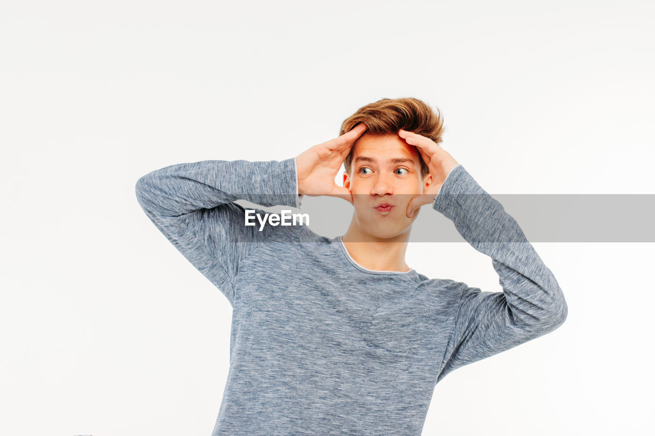 Man looking away while making face against white background