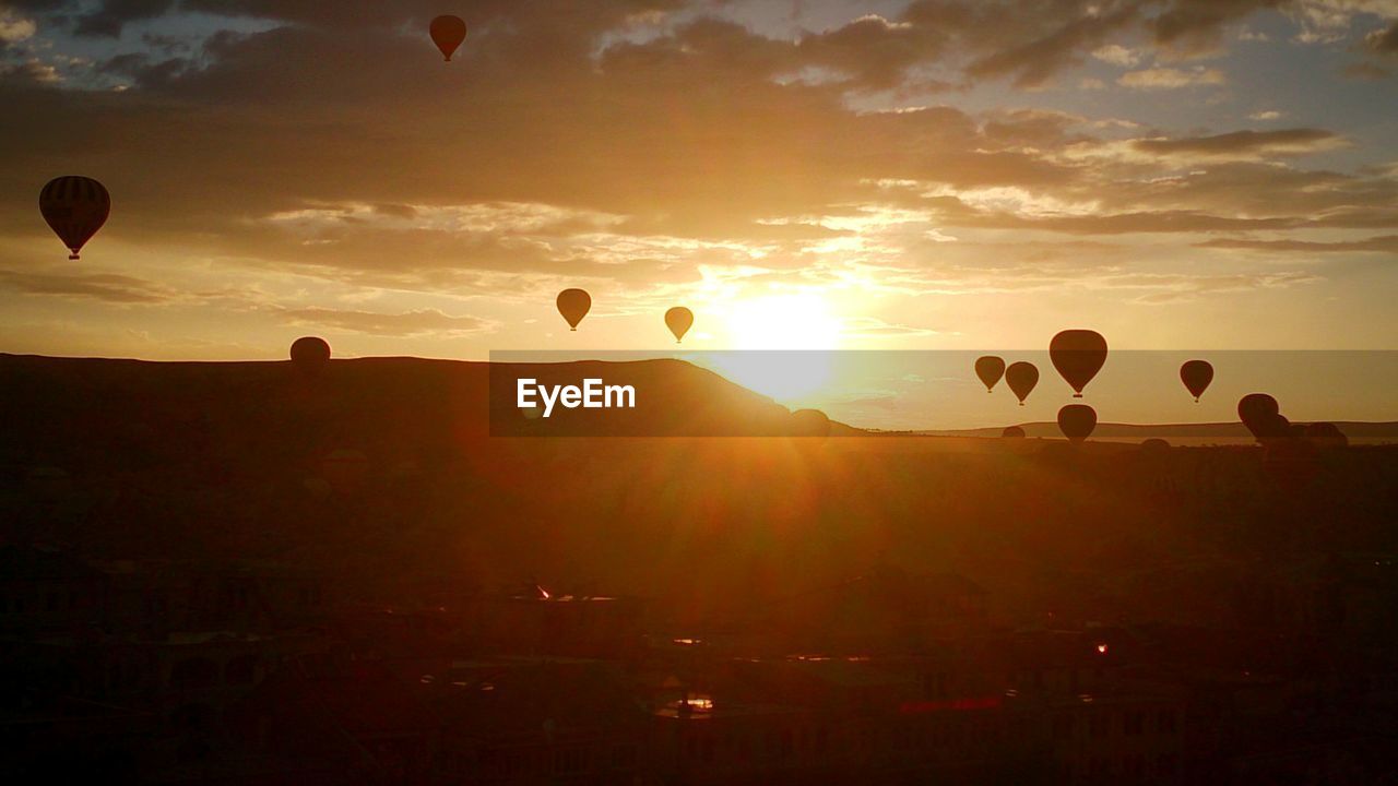 SILHOUETTE HOT AIR BALLOON FLYING OVER MOUNTAINS AGAINST SKY