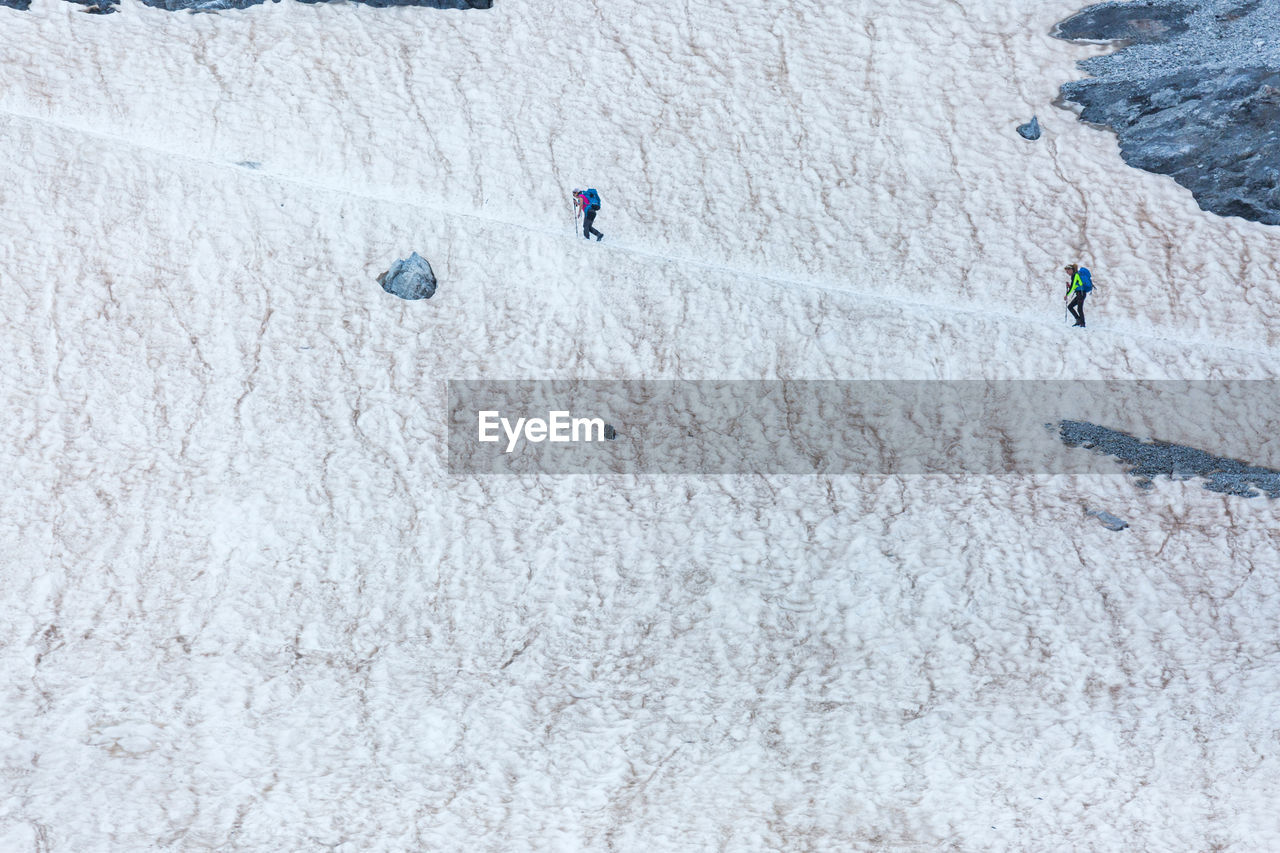 Alpinists walking on path on glacier while exploring pyrenees mountains on sunny day