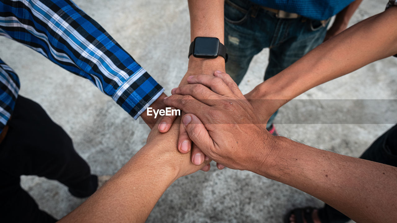 High angle view of people stacking hands outdoors