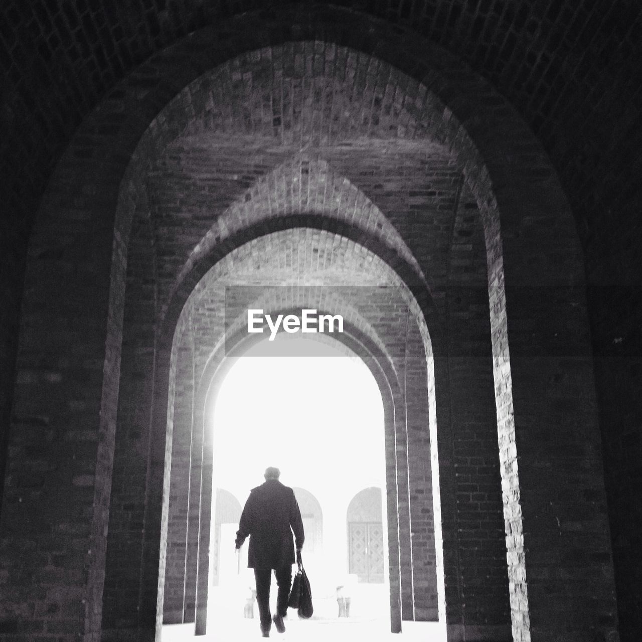 Man with bags walking under arches