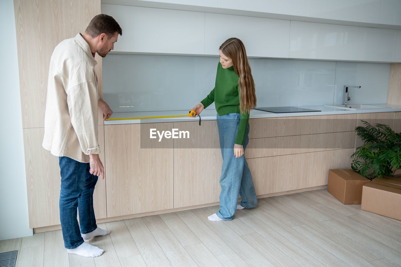 Concentrated family couple man woman measuring surface on new kitchen cabinets relocation