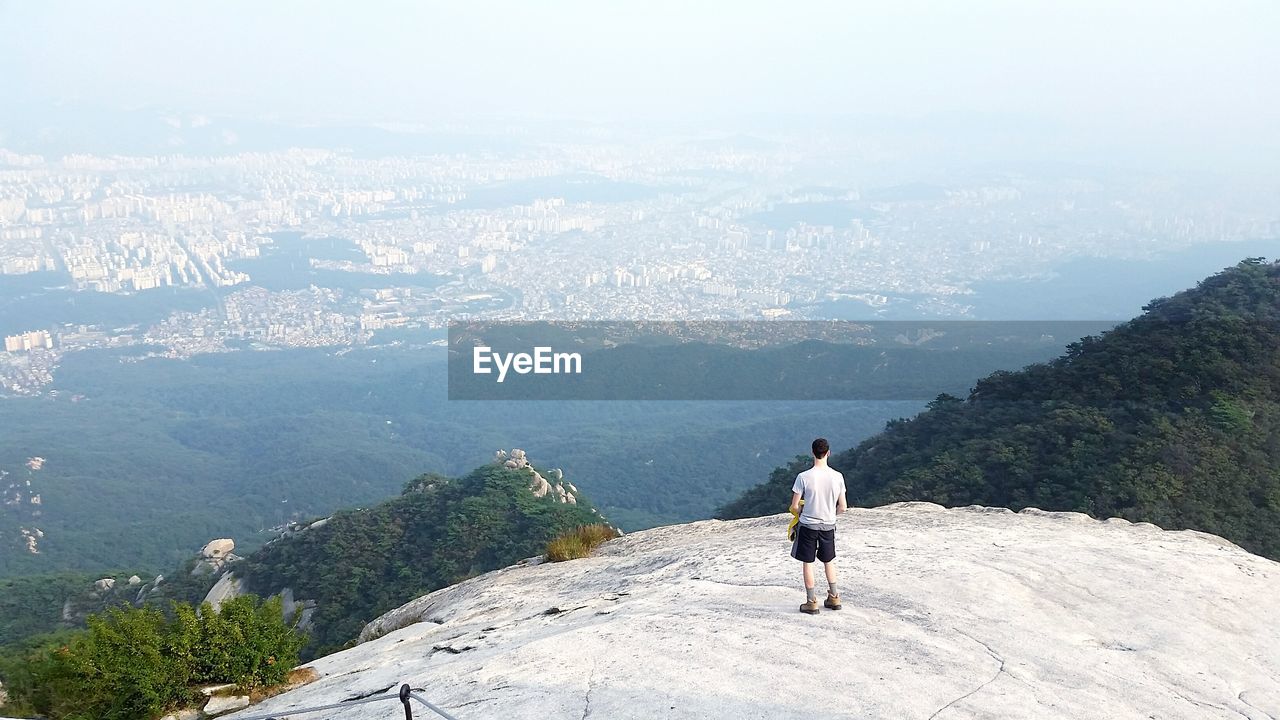 Rear view of man on cliff looking at seoul, china