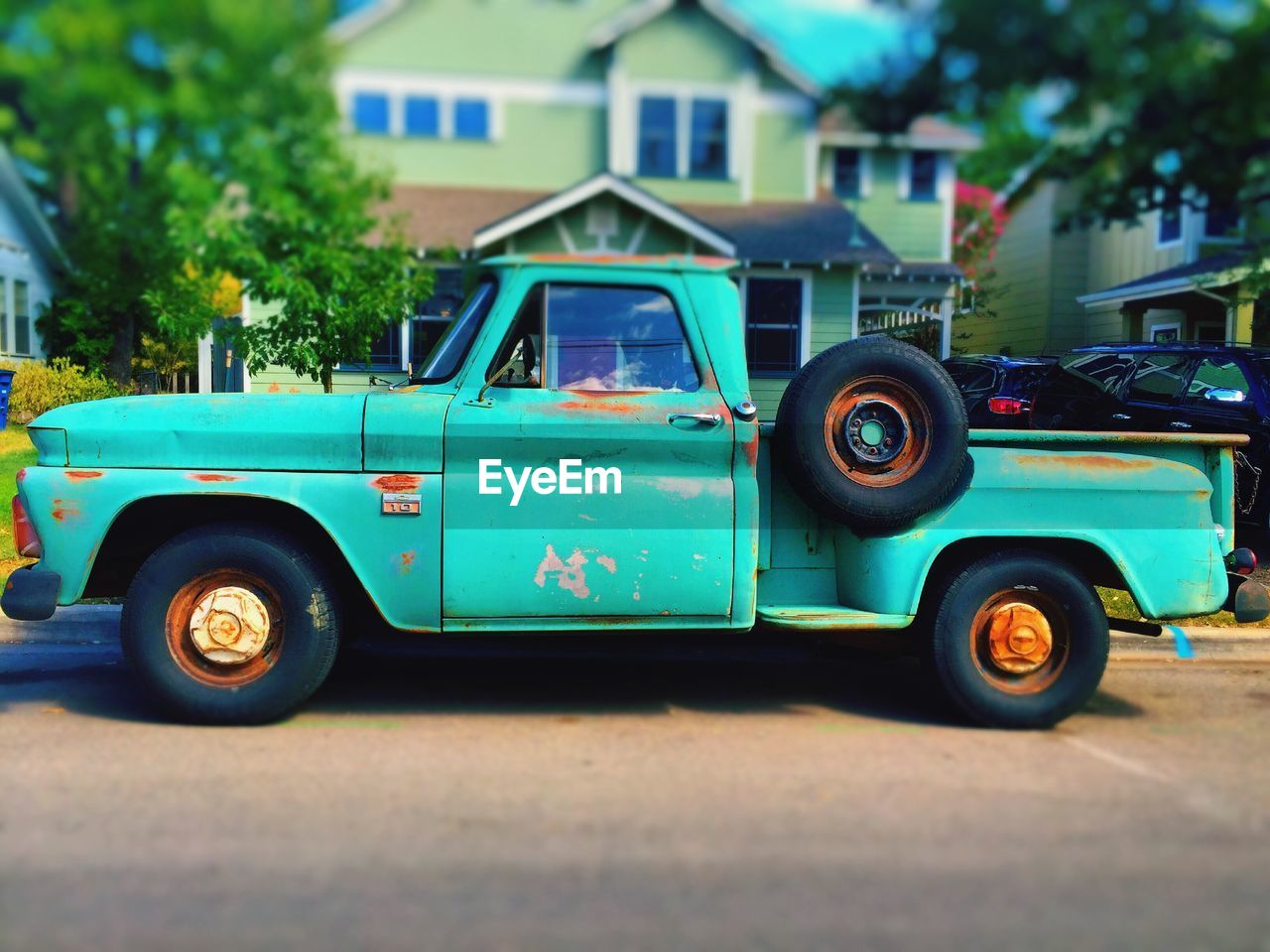 Rusty vintage pick-up truck on roadside against house