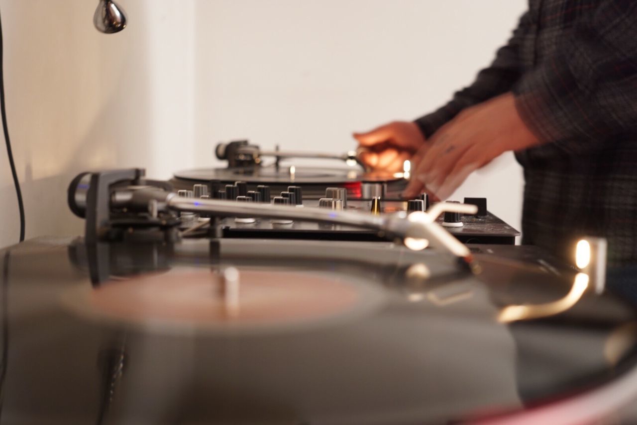 Midsection of man adjusting record on turntable