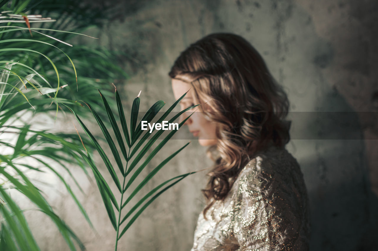 Woman with plant against wall