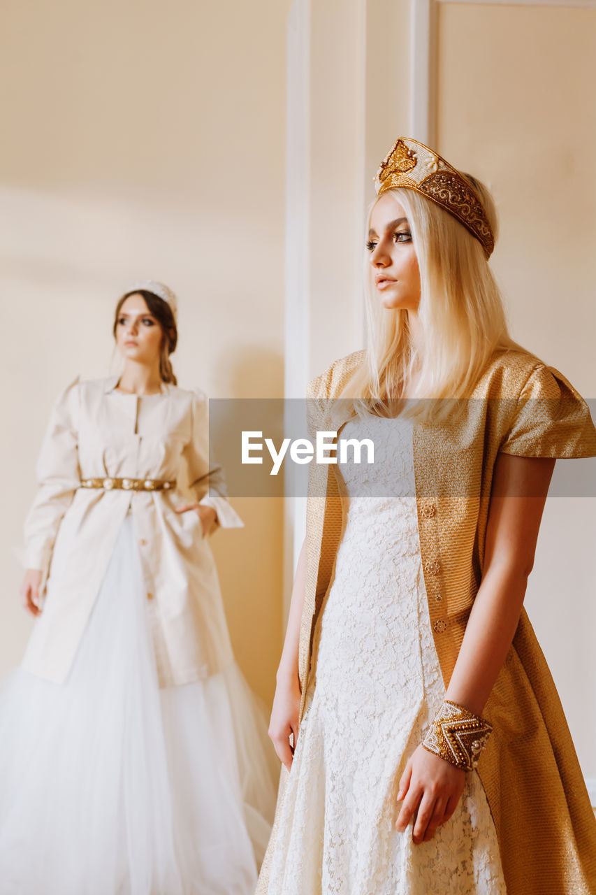 Young women in dress standing against wall