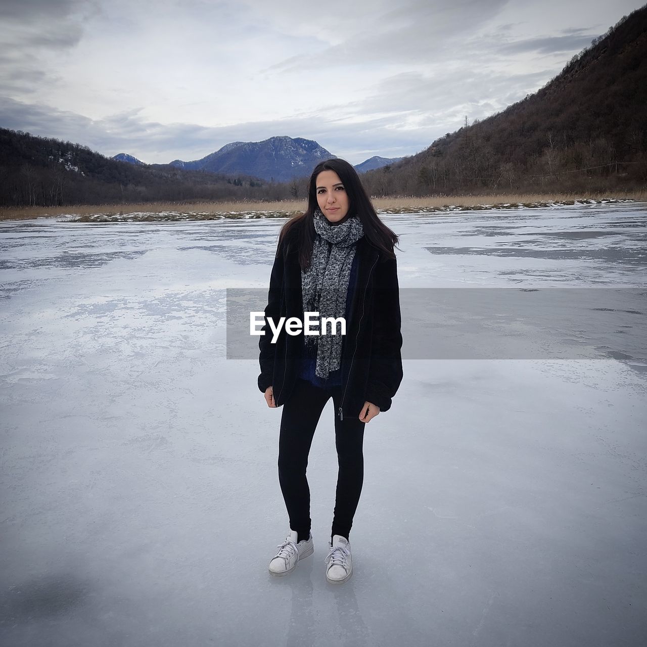 Full length portrait of woman standing on snow against sky