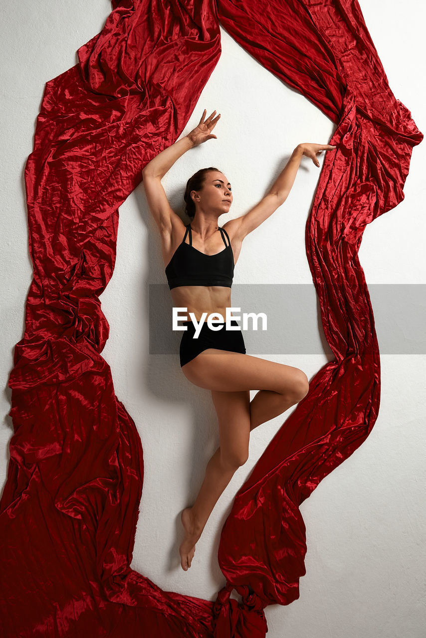 Portrait of woman standing against curtain