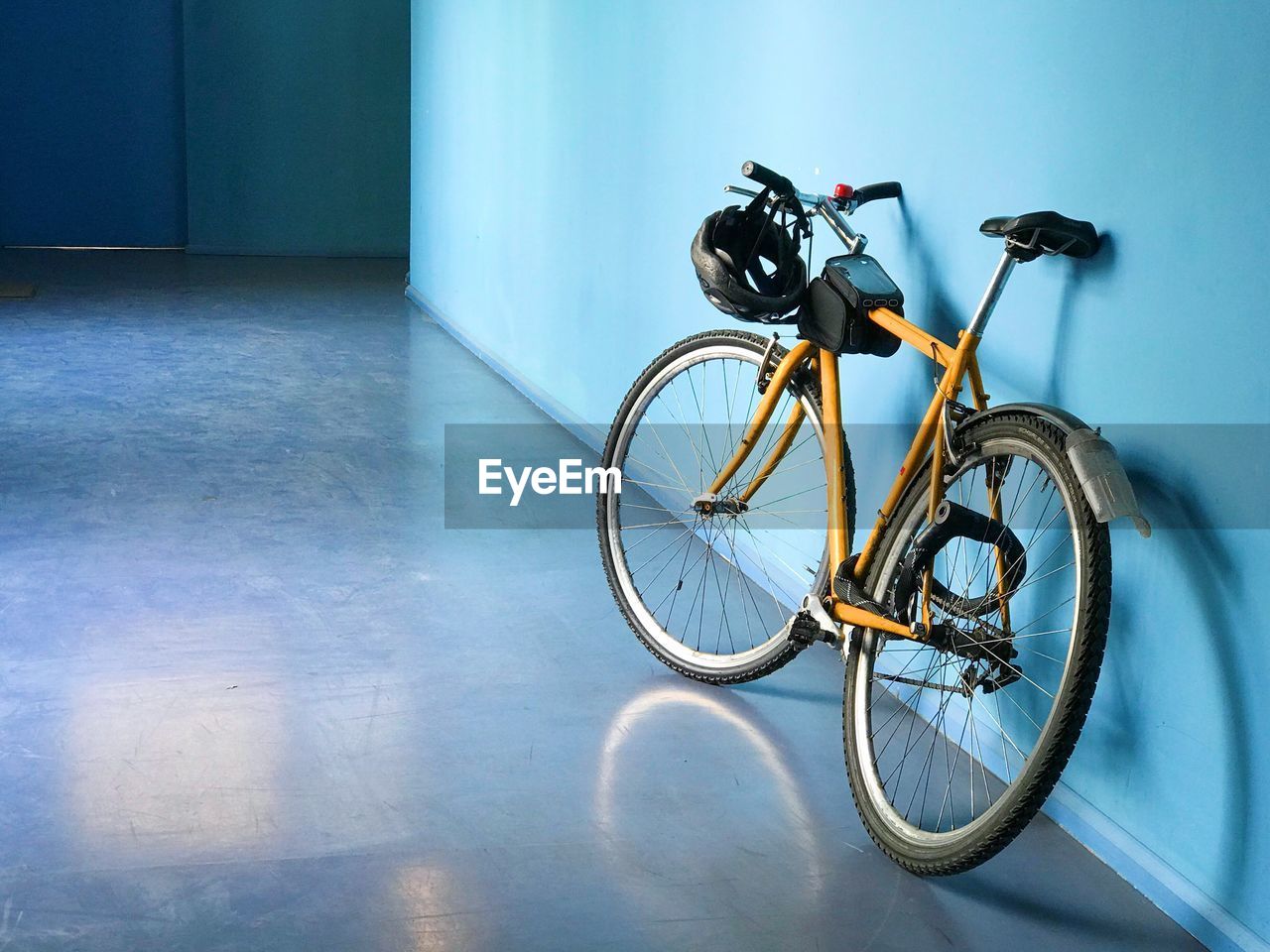 Yellow bicycle parked against blue wall in building