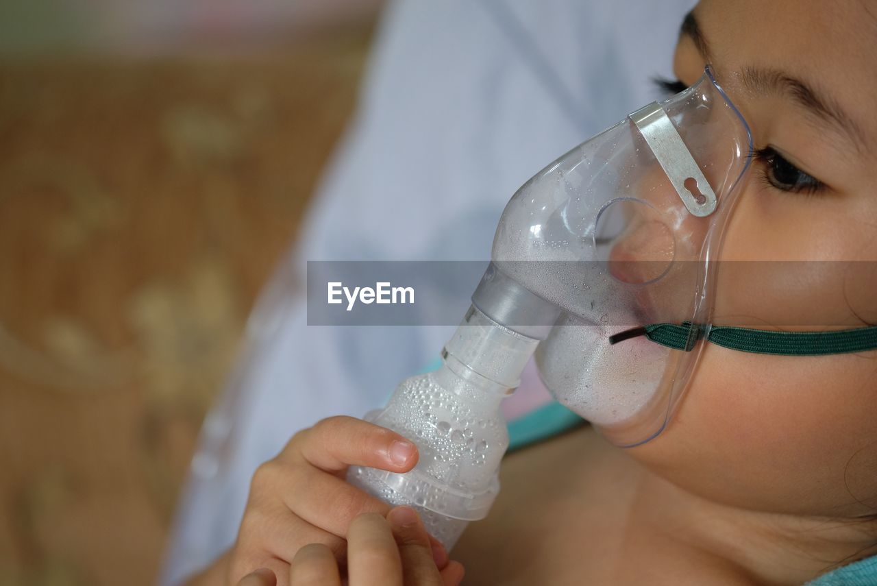 Close-up of girl wearing oxygen mask