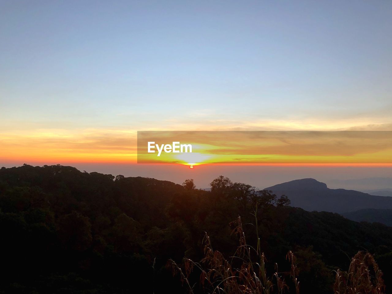 SCENIC VIEW OF SILHOUETTE MOUNTAINS AGAINST ORANGE SKY