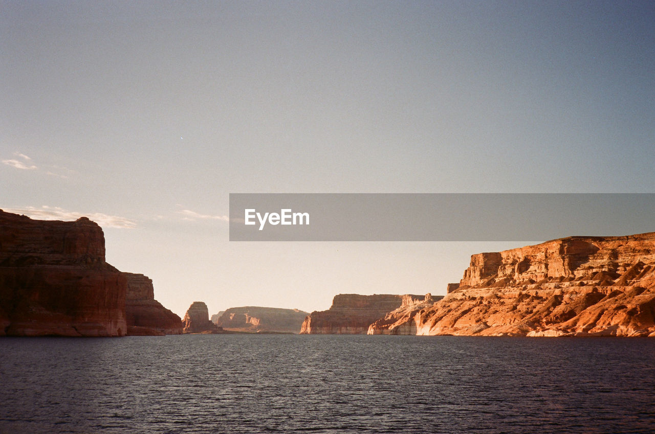 Scenic view of water and sky and the rocky red sandstone cliffs of lake powell, shot on film