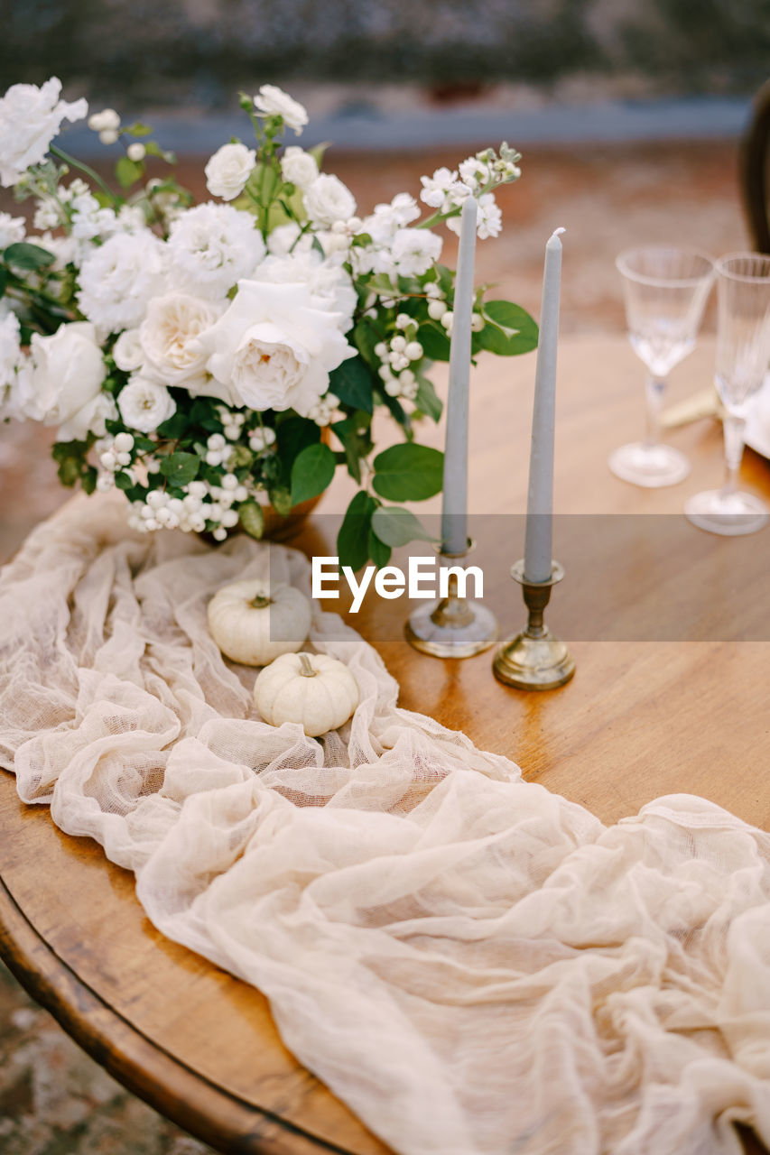 WHITE FLOWER VASE ON TABLE AGAINST GLASS WALL