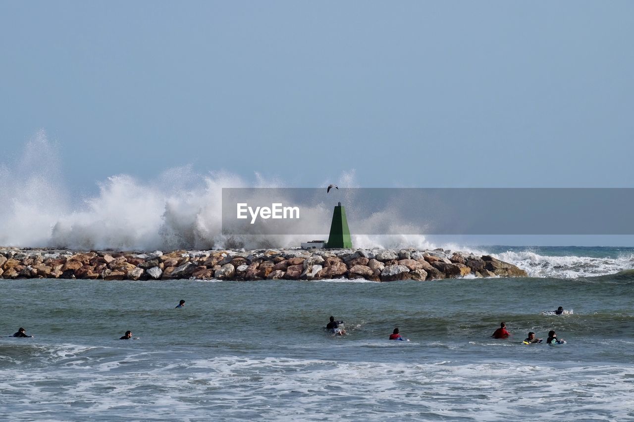 People on beach against clear sky