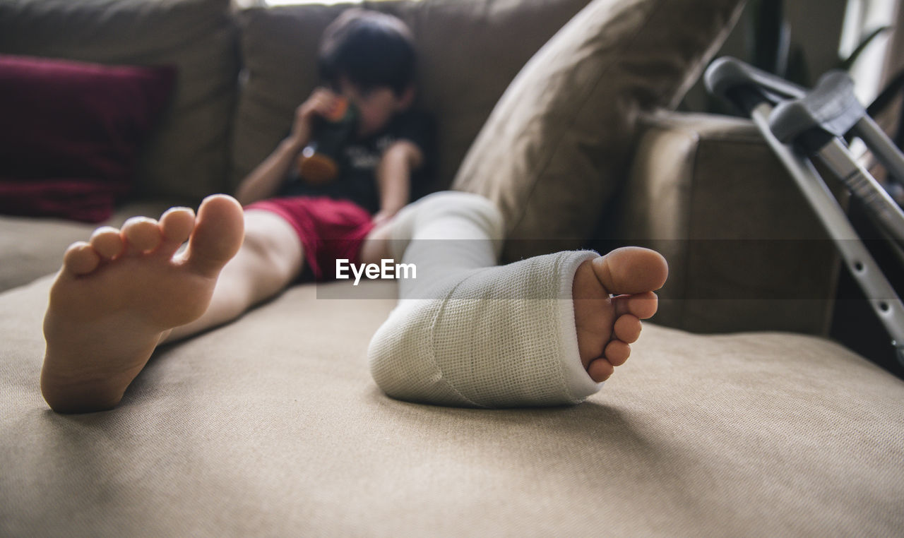 Boy with fractured leg sitting on sofa at home