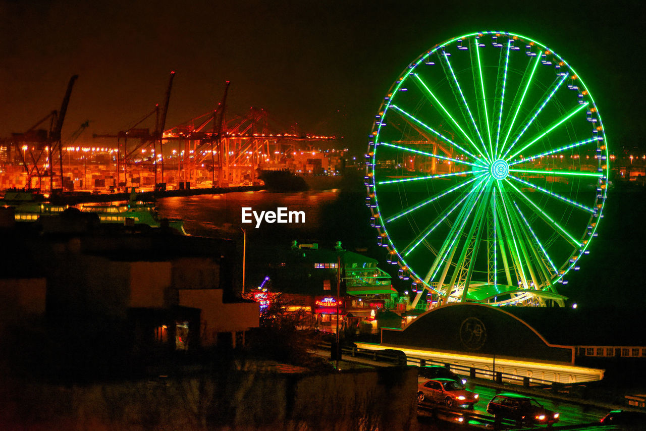 ILLUMINATED AMUSEMENT PARK AGAINST SKY AT NIGHT