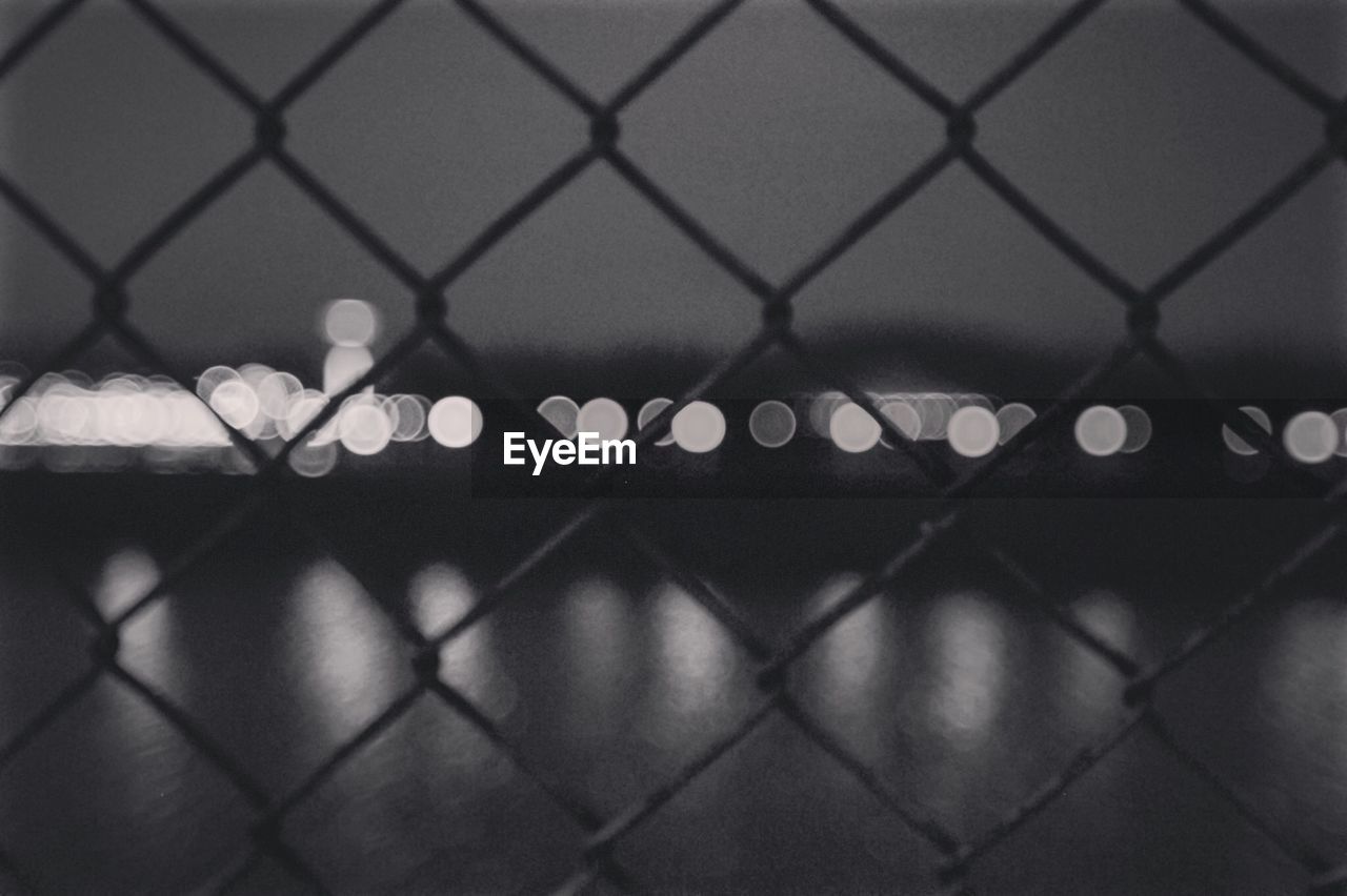 Full frame shot of chainlink fence against sky at night