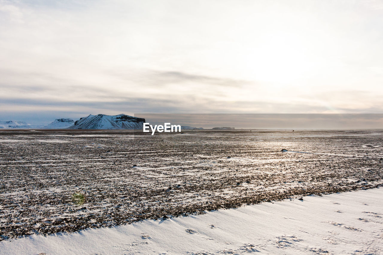 Snow field against sky during winter