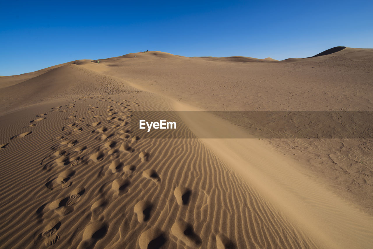 Scenic view of desert against clear blue sky