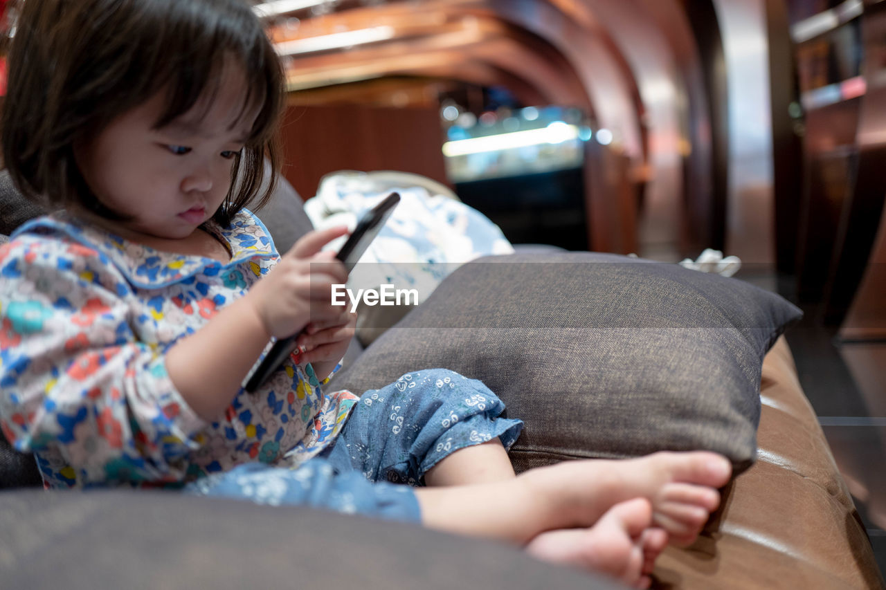 Baby girl using mobile phone while sitting at home