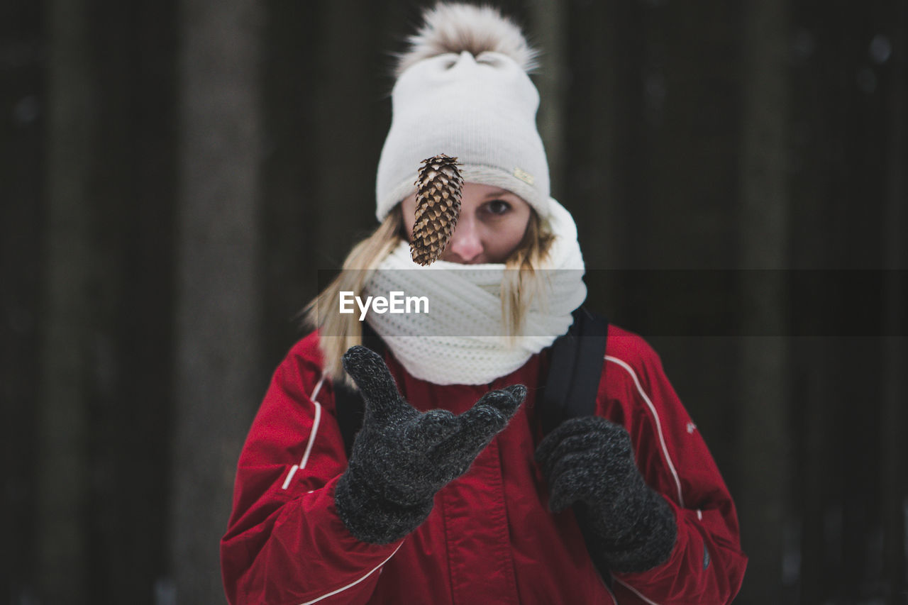 Woman catching pine cone during winter