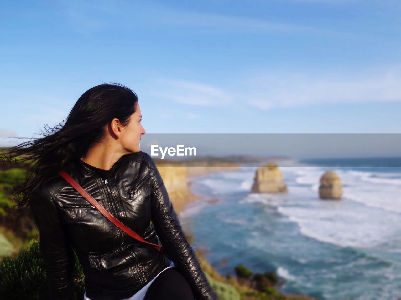 YOUNG WOMAN STANDING BY SEA AGAINST SKY