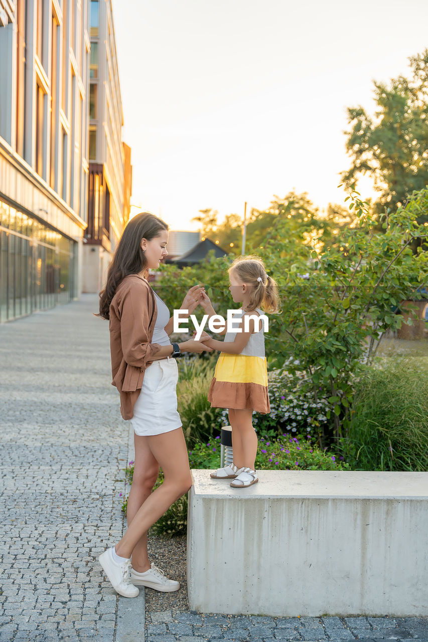 full length portrait of smiling mother and daughter walking on field