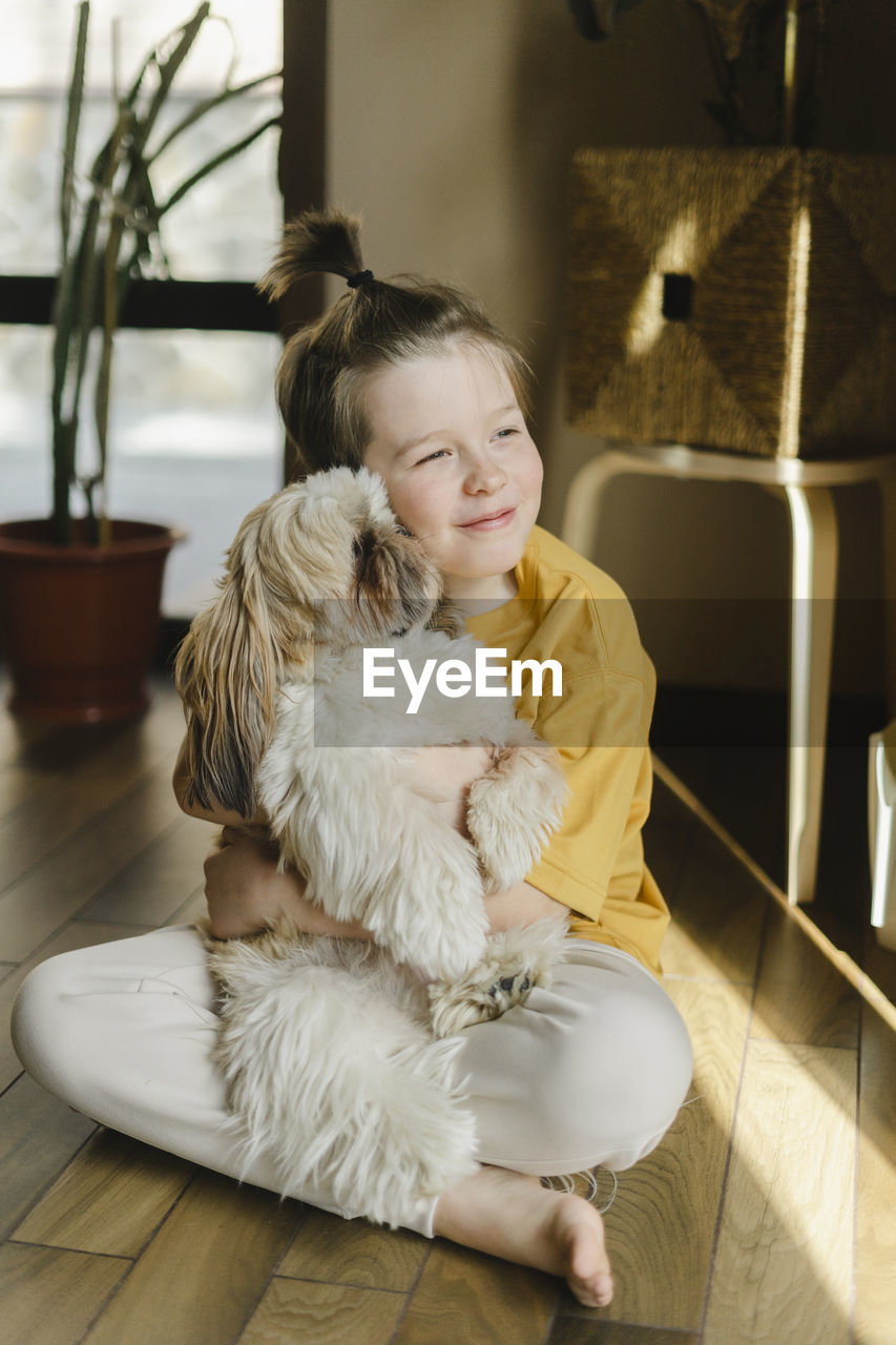 Smiling boy embracing dog at home