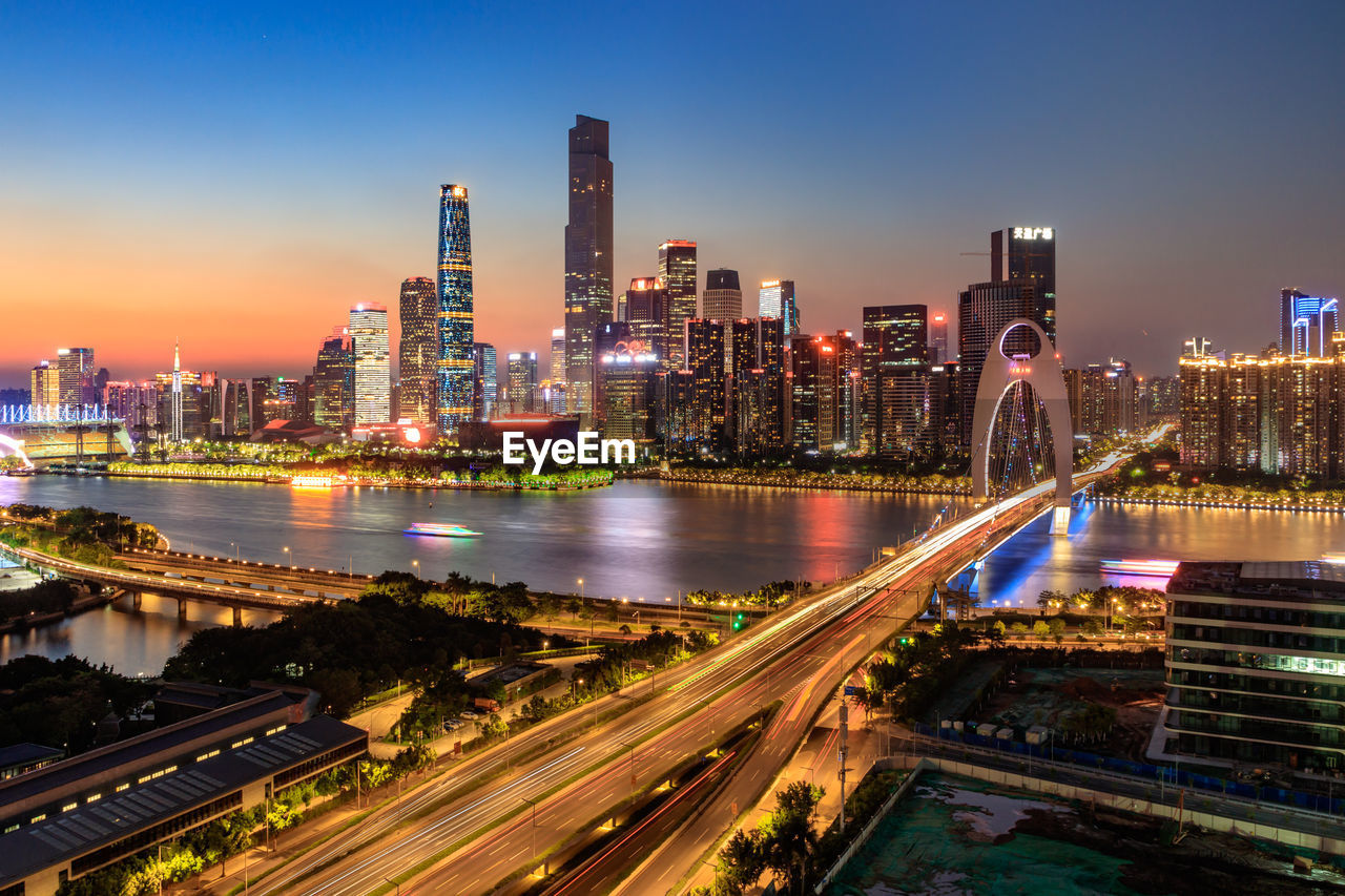 Illuminated modern buildings in city against sky at night