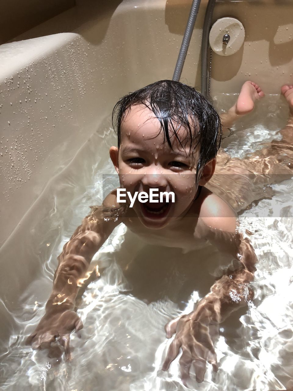 Portrait of naked boy smiling in bathtub