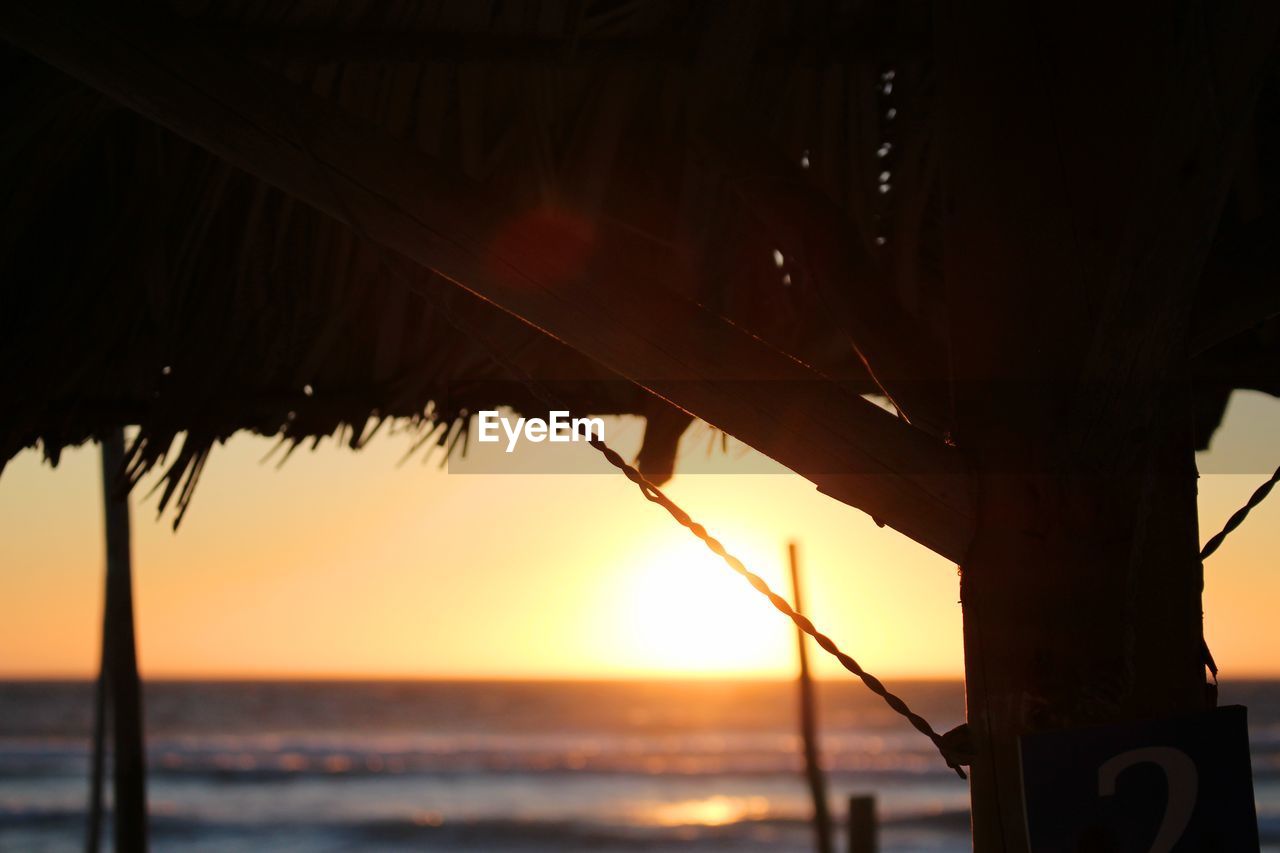 Close-up of parasol at beach during sunset