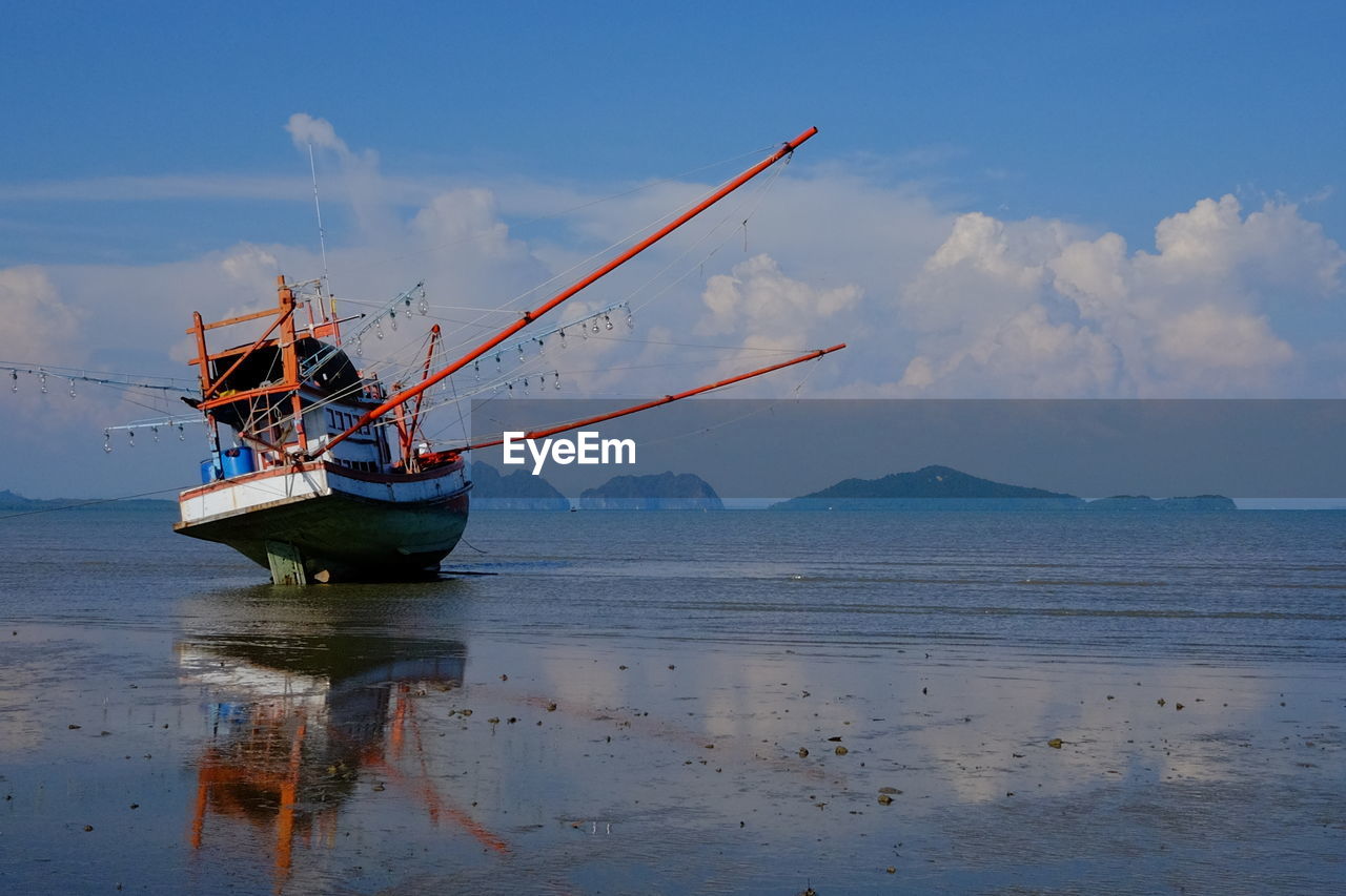 FISHING BOAT ON SHORE AGAINST SKY