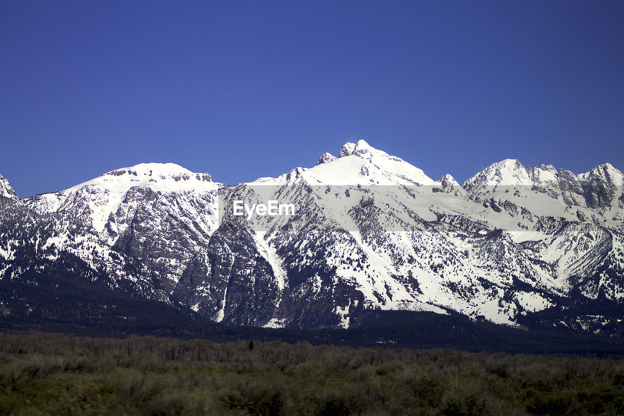 Scenic view of snowcapped mountains against blue sky