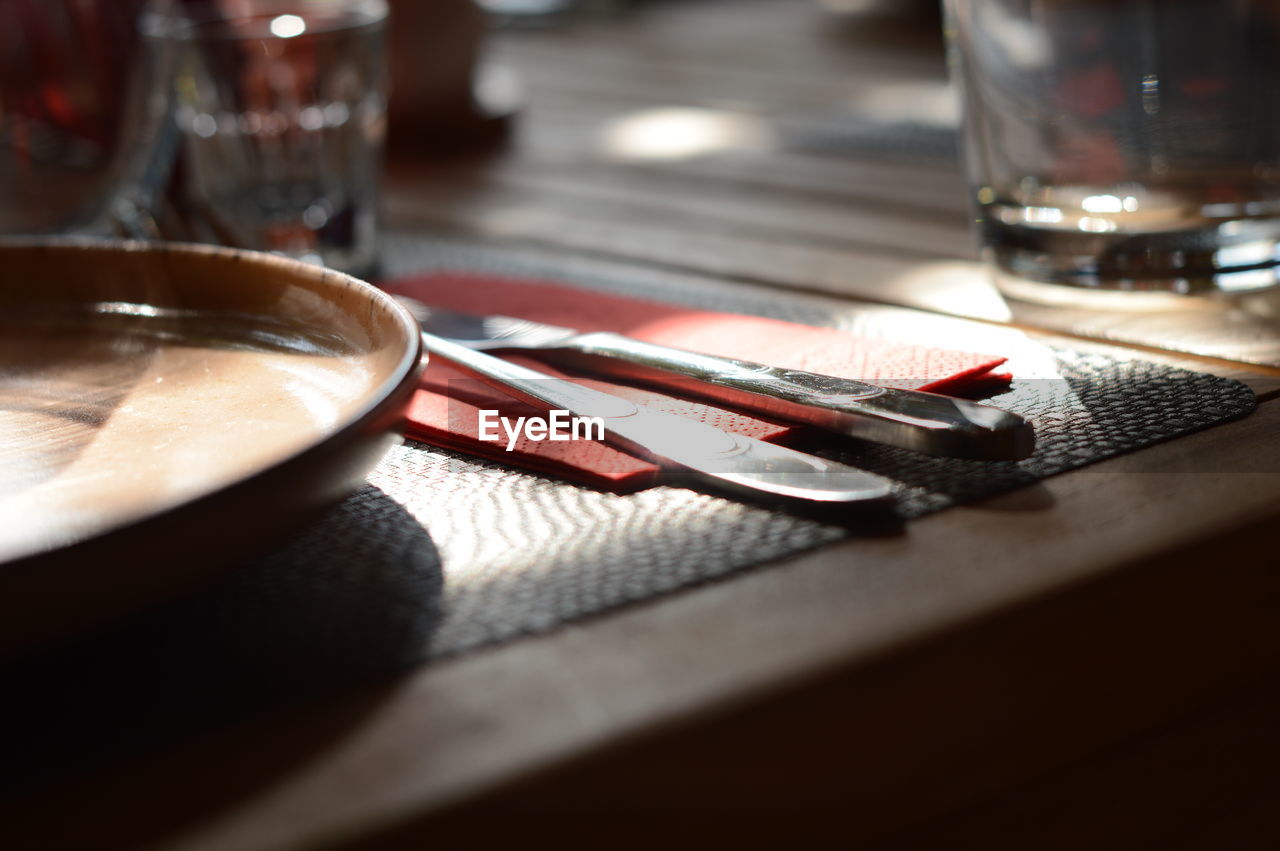 food and drink, household equipment, table, glass, drinking glass, no people, eating utensil, drink, indoors, kitchen utensil, close-up, refreshment, food, selective focus, fork, alcoholic beverage, still life, wood, restaurant, plate, place setting, tableware, freshness, water, meal, sunlight