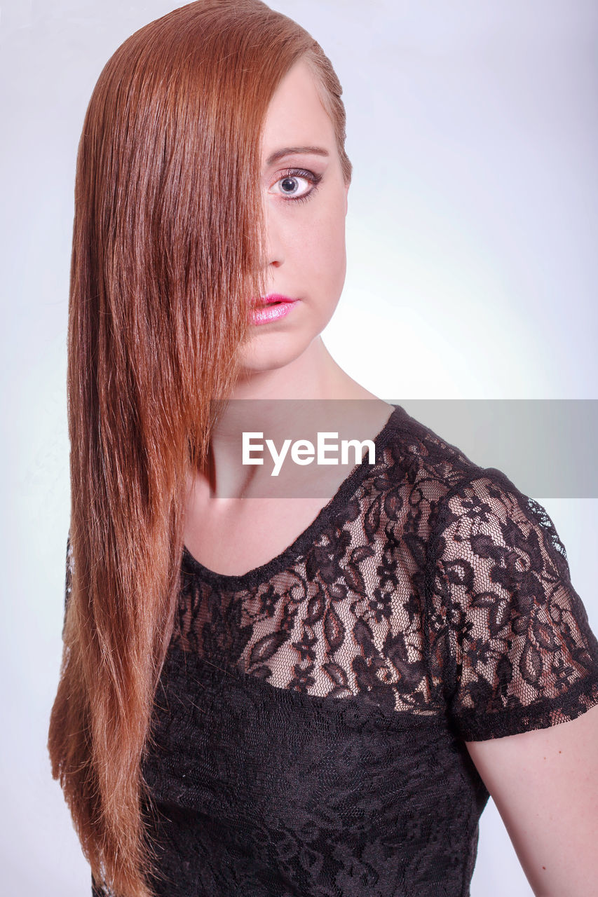 Portrait of model with long hair wearing black lace top against white background