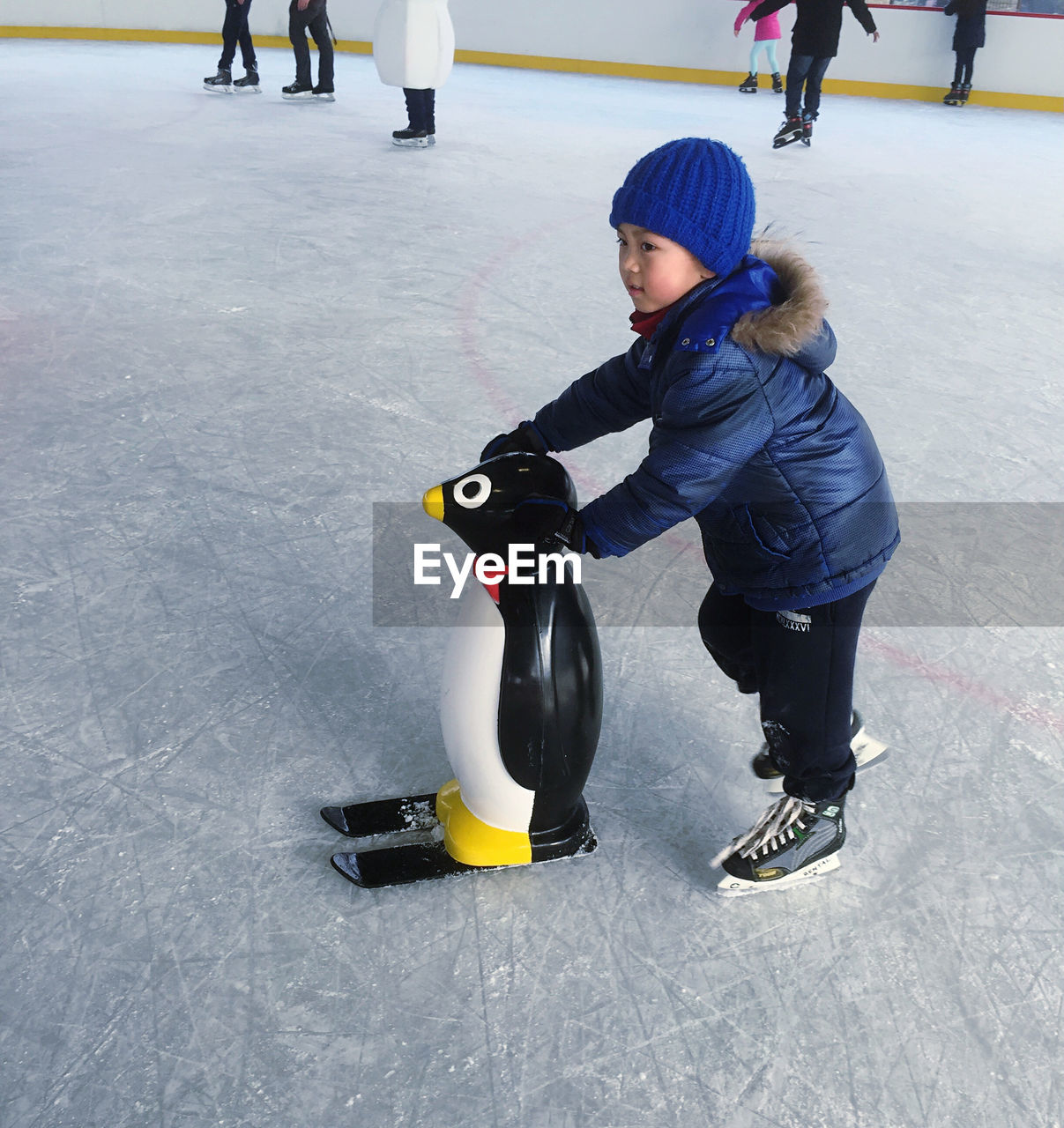 Boy learning ice skating with penguin