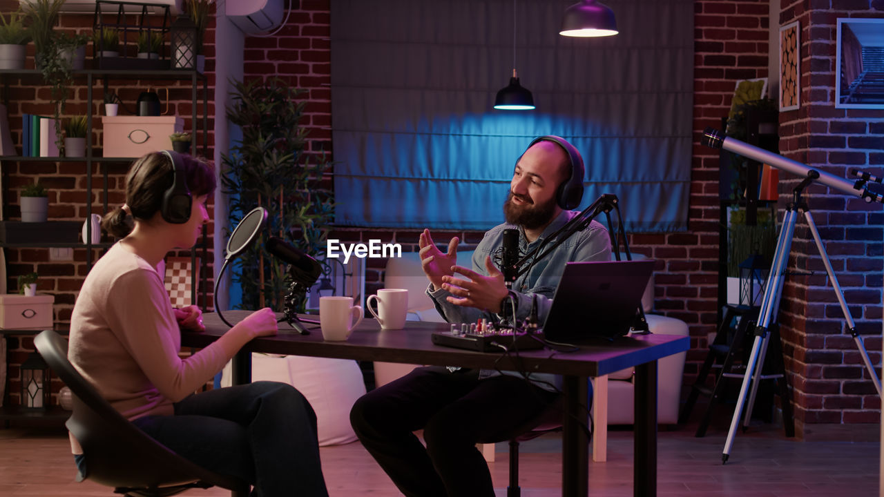 smiling friends using laptop while sitting on chair