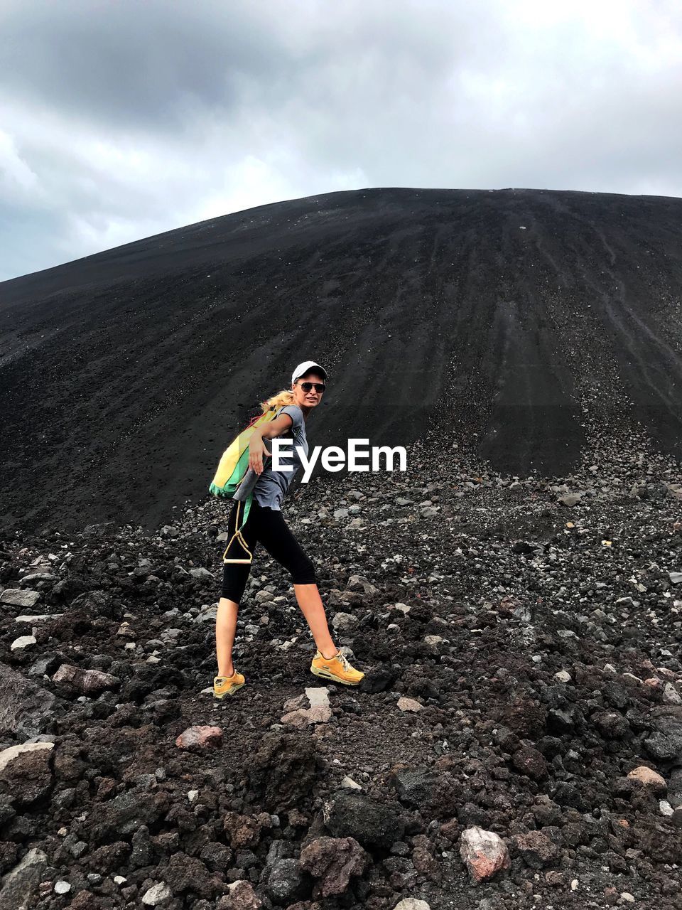 Side view of woman climbing mountain against sky