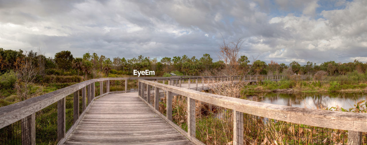 Sunset wooden bench on a secluded, tranquil boardwalk along a marsh pond in freedom park in naples