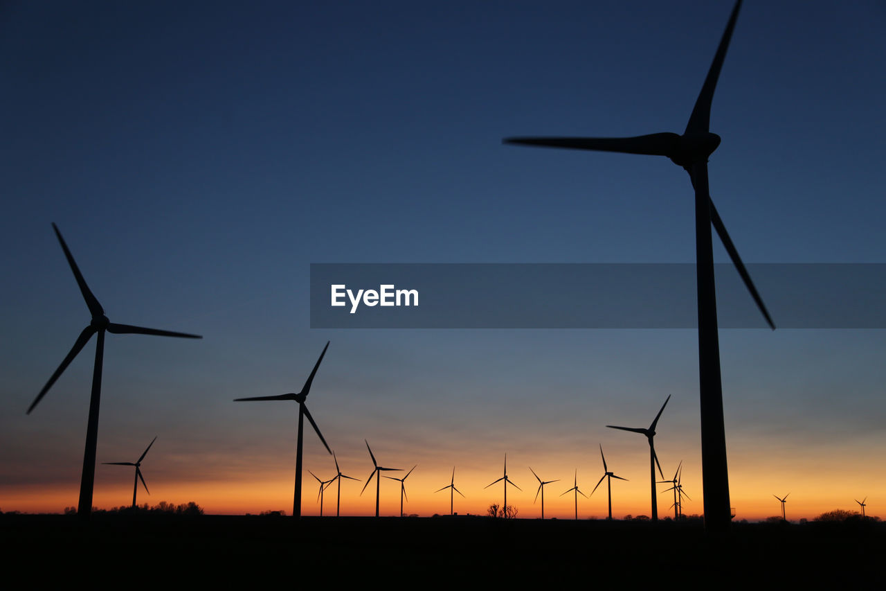 SILHOUETTE WIND TURBINE ON FIELD AGAINST SKY DURING SUNSET