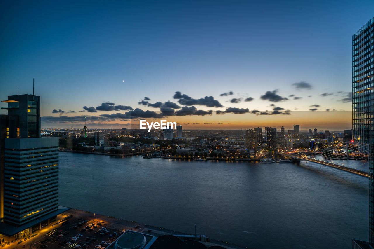 High angle view of river in illuminated city against sky