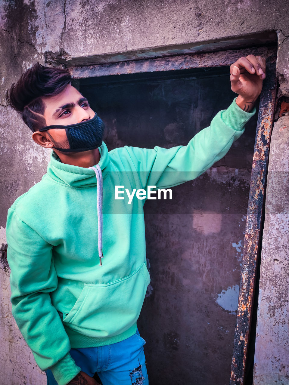 Young man wearing pollution mask while standing against wall