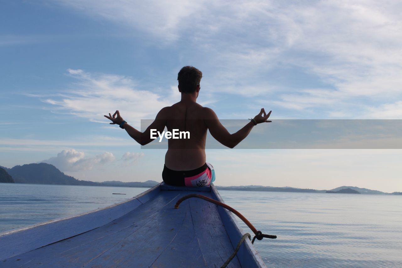 FULL LENGTH OF SHIRTLESS MAN STANDING AT BEACH